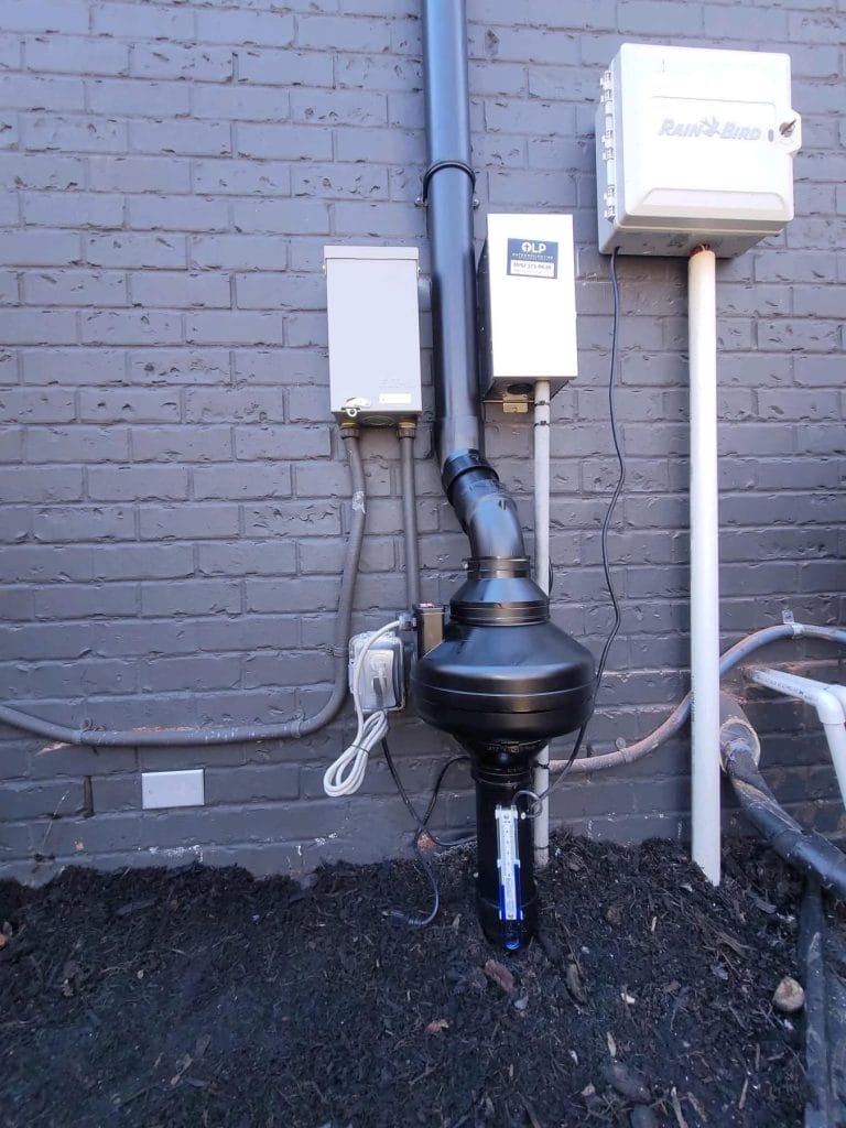 Radon mitigation system installation on exterior brick wall